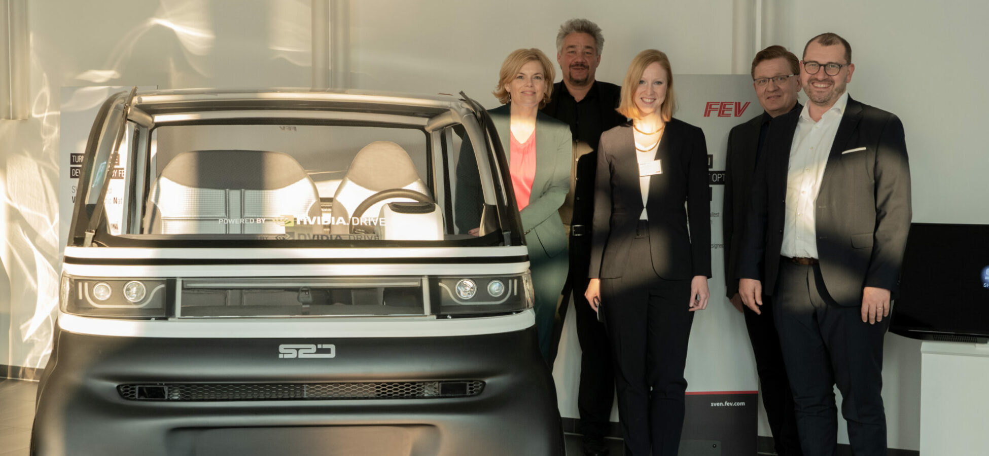 Gruppenfoto bei der FEV Group mit Annika Fohn und Julia Klöckner vor dem Fahrzeug SVEN
